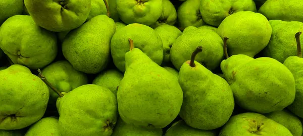 Taze yeşil armutların yoğun bir şekilde paketlendiği yakın plan çekimde, doğal dokularını, parlak renklerini ve bolluğunu vurguluyorlar, taze üretim ve sağlıklı gıda kavramları için mükemmeller..