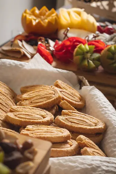 Kalp şeklindeki poğaça kurabiyelerinin yakın çekimi ile birlikte çeşitli taze kesilmiş meyveler sıcak ve davetkar bir ortamda sunuluyor. Fırın projeleri, yemek tarifleri veya zanaatkar yemek içeriği için mükemmel.