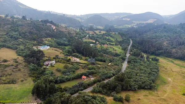 Guatavita, Kolombiya 'nın göl kenarındaki kırsal alanının çarpıcı bir görüntüsü. Görüntü kayan tepeleri, dolambaçlı yolları ve bereketli bitki ve ağaçlarla çevrili dağınık evleri yakalıyor..
