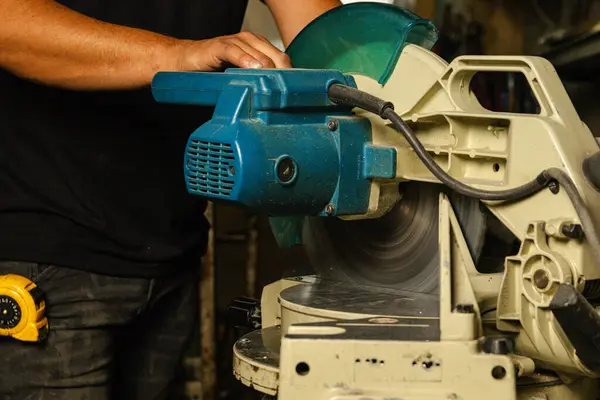 Çalışan bir işçinin elleri hareket halindeki bir metal kesici kullanarak endüstriyel bir ortamda hassasiyet ve beceri gösteriyor.