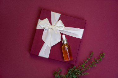 Tatil hediyeleri. Esaslı yağlı cam damlalar ve kestane rengi arka planda fiyonk. Noel ağacı dalı. Cilt bakım ürünü. Uzayı kopyala Yumuşak seçici odak