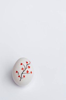 Mutlu Paskalyalar. Beyaz yumurta güzeldir, üzerinde beyaz arka planda kırmızı çiçekli güzel boyanmış bir ağaç vardır. Metni kopyalamak için yumuşak bir yay şablonu. Dikey fotoğraf