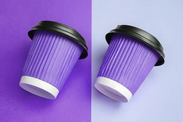 Paket kahve veya çay için iki adet mor kağıt bardağın yakın plan görüntüsü paralel konulmuş ve renkli bir tasarımcı masasına yatırılmış. Uzayı kopyala Yumuşak seçici odak