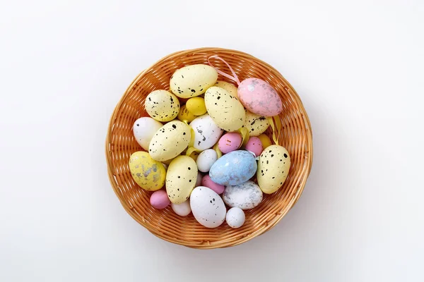 Easter Greeting card. Multi-colored eggs in wooden plate, on white background. Copy space for text. Lying flat.