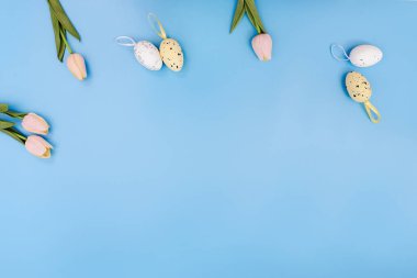Background with Yellow and pink Easter eggs and tulips on a blue background. Flat Lay, Copy Space for spring greeting text. Happy Easter