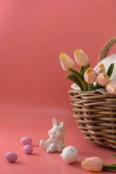 イースターの挨拶カード チューリップの入ったバスケットの近くの小さな白いイースターのおもちゃのウサギ 赤い背景のカラフルな卵 幸せな休日 スペースのコピー — ストック写真