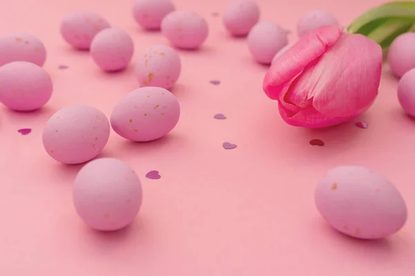 イースターグリーティングカード ピンクの背景に散在明るいピンクのチョコレートおいしい卵のクローズアップ 輝く心と繊細なチューリップをきらめく マーケティング材料 包装に使用します 幸せな休日 — ストック写真