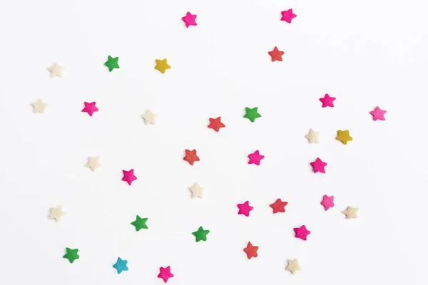 Confectionery ingredients. Multicolored sweet stars for decorating confectionery cakes, cupcakes, cakes on white background. Fun and celebration concept. Top view. Card with Copy Space for text.