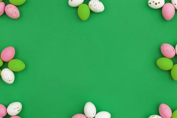 Happy Easter concept. Frame of colorful chocolate eggs arranged in shape of flowers on green background. Use for Easter or spring advertising as decorative blog image. Flat Lay Copy space