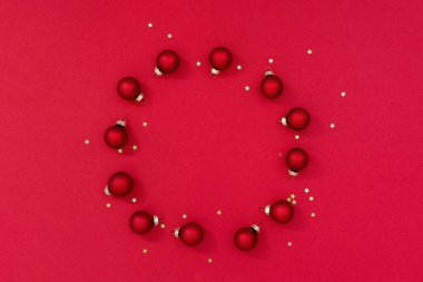 Noel kompozisyonu. Kırmızı arka planda oyuncaklardan yapılmış Noel çerçevesi. Küçük parlayan yıldızlar. Düz Yatır, Boşluğu Kopyala.