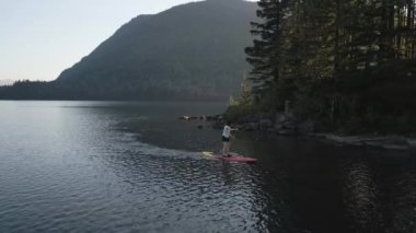Huzurlu bir gölde kürek çeken maceraperest bir kadın. Güneşli Günbatımı. Hicks Lake, Sasquatch İl Parkı Harrison Hot Springs, British Columbia, Kanada yakınlarında. Yavaş Hareket