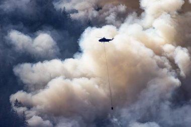 Sıcak bir yaz günü, Hope yakınlarındaki dağda, BC Orman Yangını ve Dumanı 'nın üzerinde uçan Wildfire Servis Helikopteri. British Columbia, Kanada. Doğal Felaket