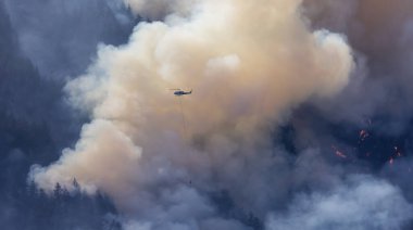 Sıcak bir yaz günü, Hope yakınlarındaki dağda, BC Orman Yangını ve Dumanı 'nın üzerinde uçan Wildfire Servis Helikopteri. British Columbia, Kanada. Doğal Felaket