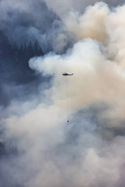 在炎热阳光明媚的夏日 野火服务直升机在霍普附近的山上飞越不列颠哥伦比亚省森林大火和烟雾 不列颠哥伦比亚省 加拿大 自然灾害 — 图库照片