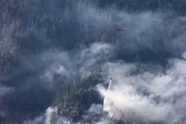 Sıcak bir yaz günü, Hope yakınlarındaki dağda, BC Orman Yangını ve Dumanı 'nın üzerinde uçan Wildfire Servis Helikopteri. British Columbia, Kanada. Doğal Felaket