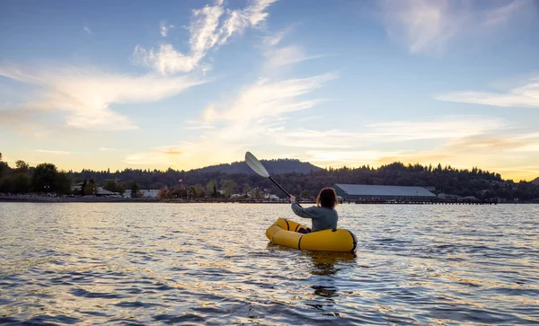Adventurous Woman Kayaking on an Inflatable Kayak in the Pacific Ocean. Sunset Sky. Port Moody, Vancouver, British Columbia, Canada. Adventure Sport Travel