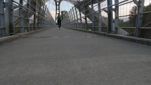 トランス カナダ ハイウェイを渡る歩行者用橋を渡って現代都市郊外の自転車に乗る女性 サンセット スカイ サリー バンクーバー ブリティッシュコロンビア州 カナダ スローモーション — ストック動画