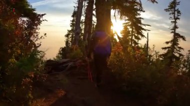Pasifik Okyanusu 'nun batı kıyısındaki Kanada dağ manzarasının tepesinde maceraperest bir kadın yürüyüşçü. Dramatik Günbatımı ve Smoky Sky. Vancouver yakınlarındaki St. Marks Zirvesi, BC, Kanada. Yavaş Sinema Sineması