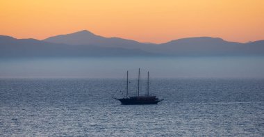 İyon Denizi 'nde dağ manzaralı bir yelkenli. Alacakaranlık Gündoğumu Gökyüzü. Katakolo, Yunanistan.