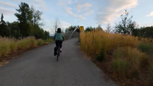 骑自行车的妇女骑在横跨加拿大公路的行人天桥上在现代城市郊区 夕阳西下萨里 温哥华 不列颠哥伦比亚省 加拿大慢动作 — 图库视频影像