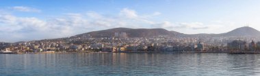 Ege Denizi kıyısındaki bir turistik kasabadaki evler ve binalar. Kusadasi, Türkiye. Renkli Gündoğumu Gökyüzü Sanatı Sunucusu. Panoramik Görünüm