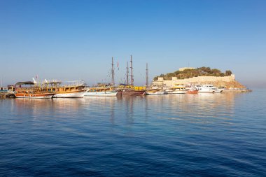 Ege Denizi kıyısındaki bir turistik kasabada Kale ile Marina 'da tekneler. Kusadasi, Türkiye. Güneşli Sabah Gündoğumu.