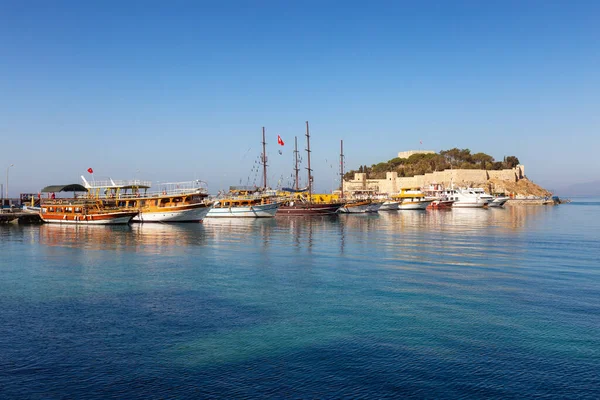 stock image Boats at Marina with Castle on the Coast in a Touristic Town by the Aegean Sea. Kusadasi, Turkey. Sunny Morning Sunrise.