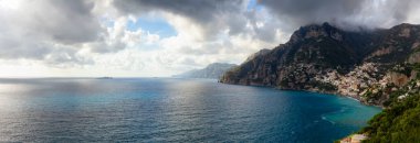 Turistik Şehir, Positano, Rocky Cliffs ve Tyrhenian Denizi kıyısındaki Dağ Manzarası. Amalfi Sahili, İtalya. Bulutlu Gök Sanatı Hazırlama. Panorama