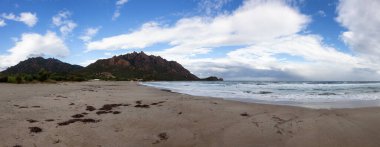 Sandy Beach at a Town on the Sea Coast. Foxi Manna, Sardinia, Italy. Mountain Background. Panorama