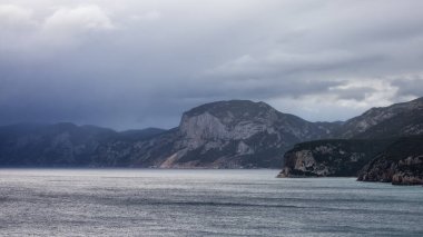 Rocky coast near Cala Gonone, Sardinia. Cloudy Sunrise Sky. Nature Background