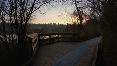 Trail by Peaceful Lake in the modern city, Deer Lake Park. Burnaby, Vancouver, BC, Canada. Colorful Winter Sunset Sky. Slow Motion Cinematic Pan