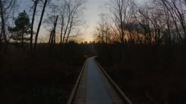 Trail in the modern city, Deer Lake Park. Burnaby, Vancouver, BC, Canada. Colorful Winter Sunset Sky. Slow Motion Cinematic Pan