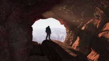 Man Standing in a Rocky Cave with Sunrays. Adventure Composite. 3d Rendering. Sunny Sunset.