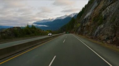 Driving on Sea to Sky Highway between Squamish and Vancouver, BC, Canada. Cloudy Winter Sunrise Sky. Slow Motion