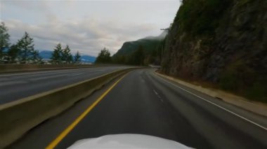 Driving on Sea to Sky Highway between Squamish and Vancouver, BC, Canada. Cloudy Winter Sunrise Sky. Slow Motion