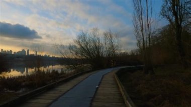 Trail by Peaceful Lake in the modern city, Deer Lake Park. Burnaby, Vancouver, BC, Canada. Colorful Winter Sunset Sky. Slow Motion Cinematic Pan.