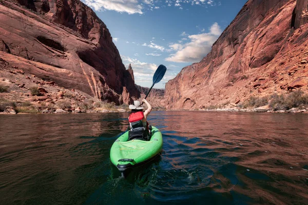 Colorado Nehri 'nde Kano kürek çeken maceraperest bir kadın. Glen Canyon, Arizona, Amerika Birleşik Devletleri. Amerikan Dağları Bulutlu Gökyüzü Sanat Yapımı. Macera Yolculuğu