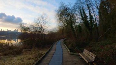 Modern şehir Deer Lake Park 'ta Peaceful Lake' in patikası. Burnaby, Vancouver, BC, Kanada. Renkli Kış Günbatımı Gökyüzü. Slow Motion Sinematik Pan.