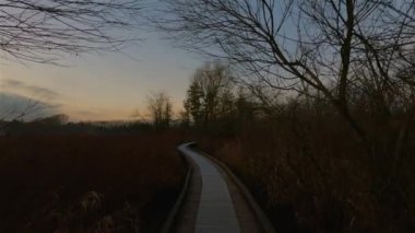 Trail by Peaceful Lake in the modern city, Deer Lake Park. Burnaby, Vancouver, BC, Canada. Colorful Winter Sunset Sky. Slow Motion Cinematic Pan
