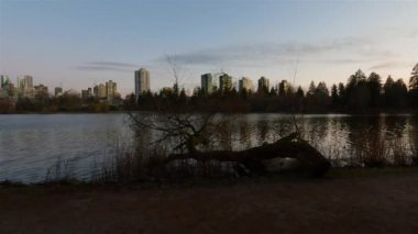 Arka planda binaların silueti olan modern bir şehrin ünlü Stanley Parkı 'ndaki Kayıp Göl manzarası. Renkli Günbatımı Gökyüzü. Vancouver şehir merkezi, British Columbia, Kanada. Yavaş Hareket