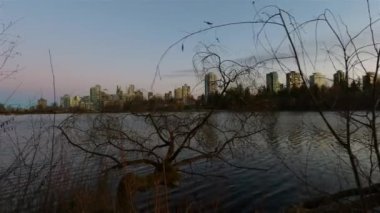 Arka planda binaların silueti olan modern bir şehrin ünlü Stanley Parkı 'ndaki Kayıp Göl manzarası. Renkli Günbatımı Gökyüzü. Vancouver şehir merkezi, British Columbia, Kanada. Yavaş Hareket