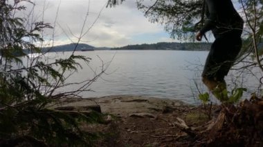 Indian Arm, Vancouver, British Columbia, Kanada 'da Rocky sahilinde koşan Runner Trail. Belcarra, Pasifik Okyanusu 'nun batı kıyısı. Bahar mevsimi güneşli bulutlu bir akşam. Yavaş Hareket