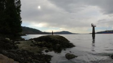 Indian Arm, Vancouver, British Columbia, Kanada 'da Rocky sahilinde koşan Runner Trail. Belcarra, Pasifik Okyanusu 'nun batı kıyısı. Bahar mevsimi güneşli bulutlu bir akşam. Yavaş Hareket