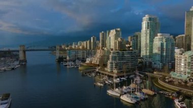 False Creek 'teki Granville Adası' nın modern şehir silueti ve arka planında dağlar olan havadan görüntüsü. Vancouver şehir merkezi, British Columbia, Kanada. Günbatımı Gökyüzü