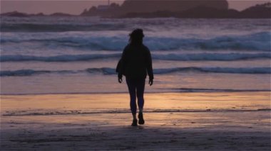 Pasifik Okyanusu 'nun batı kıyısındaki kumsalda duran maceraperest kadın. Tofino 'daki Cox Bay, Vancouver Adası, BC, Kanada. Macera Yolculuğu. Yavaş Hareket