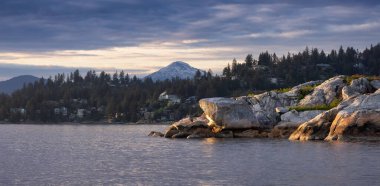 Arka planda Dağ Manzaralı Rocky Adası. Dramatik Günbatımı. Horseshoe Körfezi, Batı Vancouver, British Columbia, Kanada.