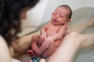 Sevimli yeni doğan bebek annesiyle banyo yapıyor..