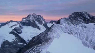 Bulutlu gündoğumunda engebeli dağ manzarasının havadan görünüşü. British Columbia, Kanada.