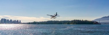Downtown Vancouver, BC, Canada - July 18, 2017: Seaplane landing in Vancouver Harbour during sunny summer day. clipart