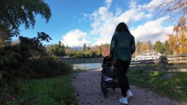 Anne, Stanley Park 'ta Bebekle Bebekleri Seawall' da gezdiriyor. Güneşli bir gün, sonbahar sezonu. Vancouver, British Columbia, Kanada.